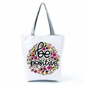 Close-up of a white tote bag featuring a vibrant floral pattern and 'be positive' text - Colorful Floral Ring Print (hl5283)