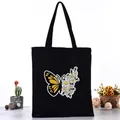 Black canvas tote bag featuring a creative yellow butterfly and white daisy print - Butterfly and Daisy Style (L4228-8) / Black