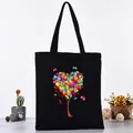 Black canvas tote bag featuring a vibrant colorful butterfly tree heart print design - Butterfly Love Tree Style (L4228-24) / Black