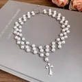 Elegant double strand pearl necklace featuring a detailed zircon cross pendant on a book cover - Silver