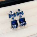 Detailed macro view of luxury vintage style square blue zircon drop earrings with silver pins - Silver-Blue