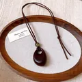 Close-up detail of vintage irregular oval wood-look pendant hanging on brown wax cord - Irregular Oval (HN9974)