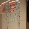 Macro view of silver mesh sweater chain featuring sparkling light blue crystal beads. - Necklace / Silver-Blue