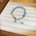 Elegante pulsera de piedras naturales azul claro con detalles de cristal y amuleto de flor dorada - Pulsera 62# (Colgante de Flor de Cinco Pétalos) / Cristal de Aguamarina Azul