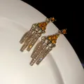 Detailed close-up of vintage gold drop earrings with amber stones and clear crystals - Earrings / Gold Brown