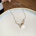 Detailansicht der Halskette mit Muschel und Seestern auf einem weißen Keramikteller. - Schlangenkette Muschel Stil