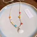 Detailed close-up of a vibrant wax cord necklace with beads and a white seashell pendant - Colorful Beaded Shell Style