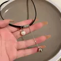 Dettaglio di un girocollo in pelle nera con ciondoli a forma di perla e sfera d'argento - Nero