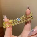 Mano sosteniendo un conjunto de pulseras de cuentas de cristal amarillo y azul. - Pulsera 5# (Conjunto Apilado y Con Caja de Regalo) / Cuarzo Rutilado Amarillo