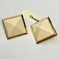 Macro view of beige square resin stud earrings with gold metal frame and pyramid design - Gold-Beige