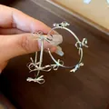 Macro shot of large silver hoop earrings featuring multiple metallic bow decorations. - Multi-Bowknot Hoop (Silver Post) / Silver
