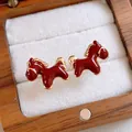 Detailed view of red enamel horse stud earrings in a wooden jewelry box. - Gold Enamel Horse (6#) / 925 Silver Needle / Red