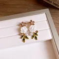 Macro detail of elegant floral earrings with white roses, green leaves, and pearls - White Flower Silver Post Earrings