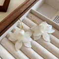 Detailed macro view of elegant white resin flower earrings inside a velvet jewelry box - Flower (HE20328) / White