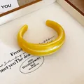 Primo piano di un audace bracciale rigido in resina gialla effetto marmo per donna. - Giallo