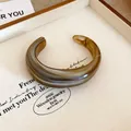 Dettaglio di un elegante bracciale rigido aperto in resina ambrata marmorizzata lucida - Grigio