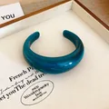 Primo piano di un bracciale rigido in acrilico blu petrolio con finitura in resina lucida - Verde Smeraldo