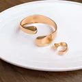 Detail view of irregular gold-colored open cuff bracelet and matching smooth ring set - Bracelet and Ring Set / Gold