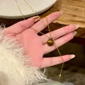 Macro detail of a vintage gold-plated necklace with a polished brown tiger's eye stone bead. - Gold