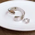 Macro view of irregular silver elliptical open bangle and ring with mirror finish - Bracelet and Ring Set / Silver