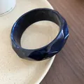 Macro detail of a dark navy blue faceted resin bangle on a minimalist ceramic plate - Geometric Faceted Marble Style / Blue