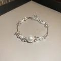 Gros plan élégant d'un bracelet réglable en perles blanches et métal de style français - Style Extension Perle Métal Irrégulière / Argent / Perle