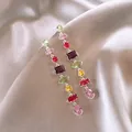 Detailed close-up showing colorful irregular gemstone long tassel drop earrings on silk fabric - Tassel Style (WE2950) / Colorful