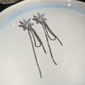 Primer plano de pendientes de copo de nieve con pedrería brillante y una fina perla - Estilo Copo Perla Cadena Fina Borla 35