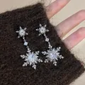 Primer plano de pendientes colgantes de copo de nieve sobre tela de punto - Estilo Colgante Doble Copo Circonia 43