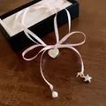 Detailed view of pink ribbon necklace with silver heart locket, pearl and star charm - Pink