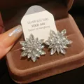 Close-up detail of sparkling floral silver stud earrings set in a brown velvet gift box - Gold