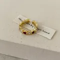 Gros plan d'une bague ouverte dorée avec des détails de cœur en émail rouge et cristal. - Or avec Rouge (Cœur)