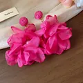 Dettaglio ravvicinato di orecchini a fiore in chiffon rosa acceso con rafia e perla - Rosa Rosso