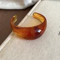 Vintage amber marble patterned resin cuff bracelet on textured book background - Open Marble Style / Brown