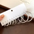 Nahaufnahme eines minimalistischen silbernen Creolen-Sets mit Perlen und Texturdetails. - 12 Paare Set / Silber