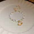 Vue détaillée d'un élégant bracelet de perles dorées avec un charm en coquillage - Style Boucle Réglable Perle Coquillage / Or
