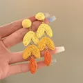 Detailed view of woven raffia earrings with gradient yellow and orange heart shapes. - Yellow (HE30706)