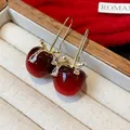 Detailansicht roter Harz-Apfel-Ohrhaken mit Zirkon-Akzenten in einer Schmuckschatulle - Haken-Stil / Rot