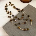 Detailed close-up of vintage tiger eye beaded layered necklace on grey texture background - Double-Layer Beaded (HN10367) / Gold Brown
