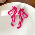 Close-up of hot pink matte ribbon bow earrings with sparkling rhinestone accent - Pink