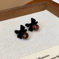 Dettaglio macro di eleganti orecchini a perno con fiocco nero floccato e perline. - Stile con Fiocco (HE29111) / Nero