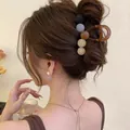 Détail d'une pince à cheveux française géométrique marron sur une coiffure rétro - Café Rond