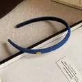 Detailed view of a navy blue slim flocked headband with a gold Love engraved metal tag - Dark Blue