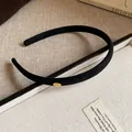 Close-up detail of black flocked thin headband with an elegant gold Love metal tag - Black