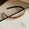 Macro view of brown flocked fabric headband with gold Love charm detail - Brown