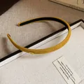 Close-up of a mustard yellow fabric headband with a gold 'Love' tag on a white box - Yellow