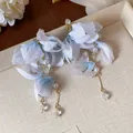 Dettaglio di eleganti orecchini a fiore in tessuto blu e bianco con perle e cristalli - Blu