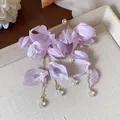 Dettaglio di eleganti orecchini a fiore in tessuto lilla con perle e cristalli lucenti - Viola Chiaro