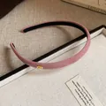 Detailed view of a pink flocked fabric headband featuring a gold Love charm detail - Pink