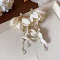 Dettaglio ravvicinato di orecchini eleganti a fiori in tessuto con perle e oro. - Giallo